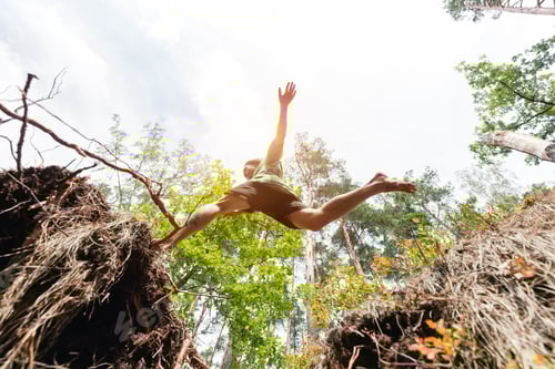 Preview: Young man making a jump in the forest.