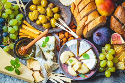 Preview: Cheese plate served with fruits, honey and snacks, top view. Assorted cheese background.