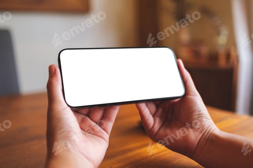 Preview: Mockup image of a woman holding and using mobile phone with blank desktop at home