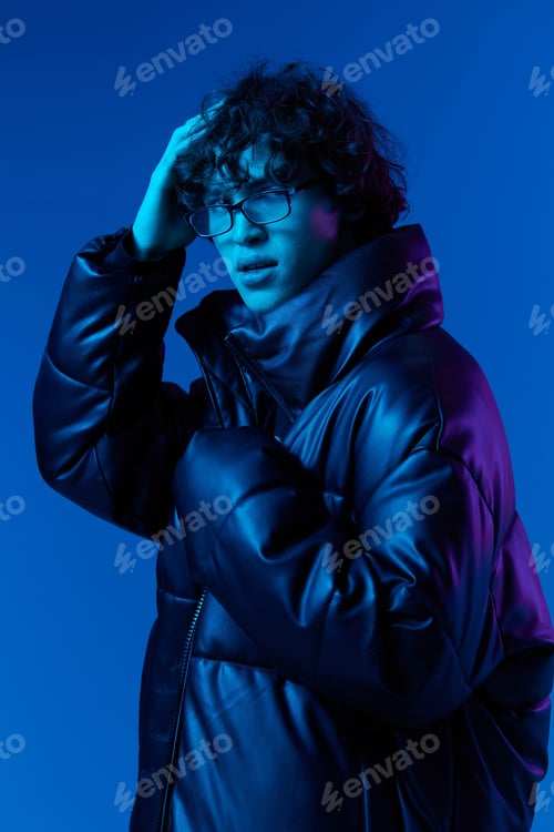 Preview: Man in winter down jacket model poses with a smile with glasses, hipster lifestyle, portrait blue