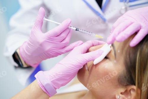 Preview: Aesthetic doctor injecting botox into the forehead of her middle-aged patient