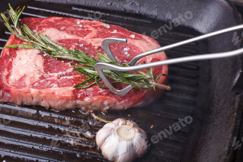 Preview: forceps greasing beef steak by rosemary