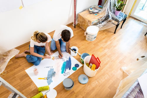 Preview: Young couple sitting on the floor choosing color for painting the wall in their home.