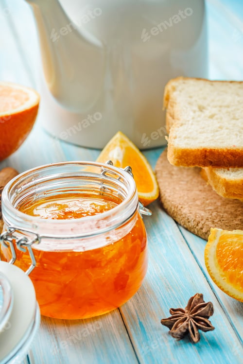 Preview: Close up of homemade orange jam in glass jar on blue background