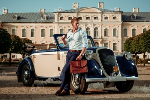 Preview: Confident wealthy young man with briefcase near classic convertible