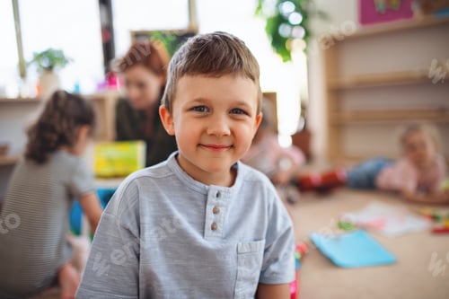 Preview: Portrait of small nursery school boy indoors in classroom, looking at camera
