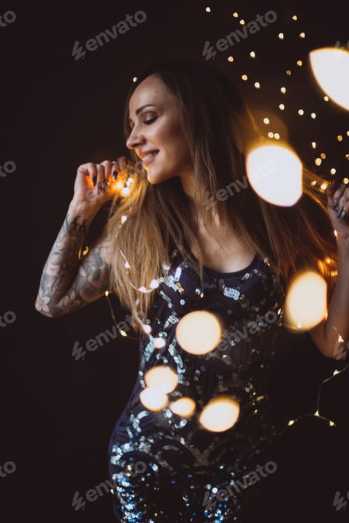 Preview: Beautiful smiles woman celebrate the new year on a Christmas background , with a sparkler