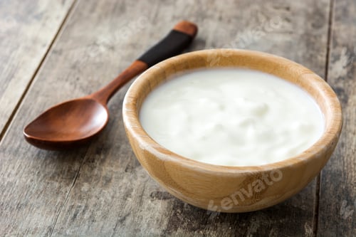 Preview: Wooden spoon and bowl of yogurt resting on rustic table