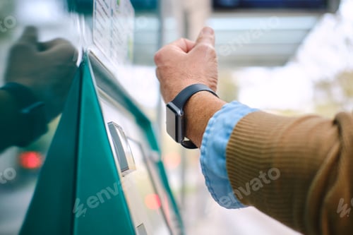 Preview: side view detail of adult Man paying for public transport using smartwatch. unrecognizable person