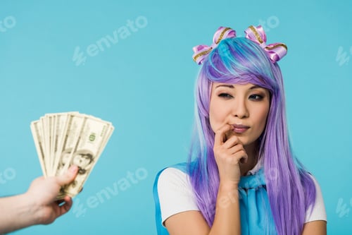 Preview: Cropped view of man holding dollar banknotes and pensive asian anime girl isolated on blue