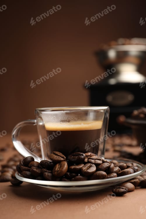 Preview: Cup of hot coffee, grinder and beans on brown background, closeup