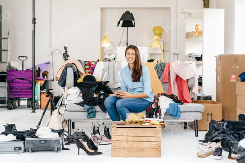 Preview: Portrait of smiling young woman with cell phone surrounded by fashion