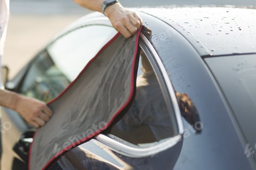 Preview: Worker washing car at car wash and wipes vehicle with rag.