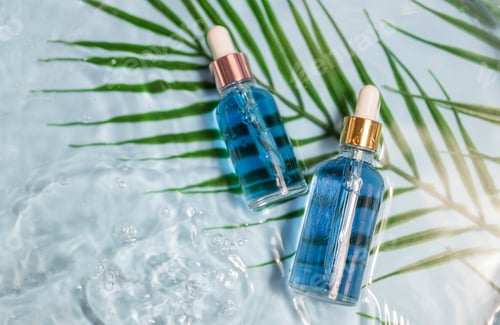Preview: cosmetics bottles transparent for skin care in water on a blue background with a palm leaf