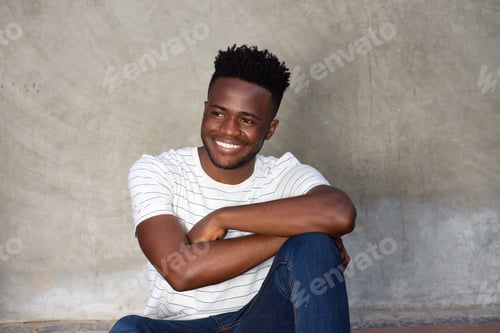 Preview: handsome smiling african man sitting by wall