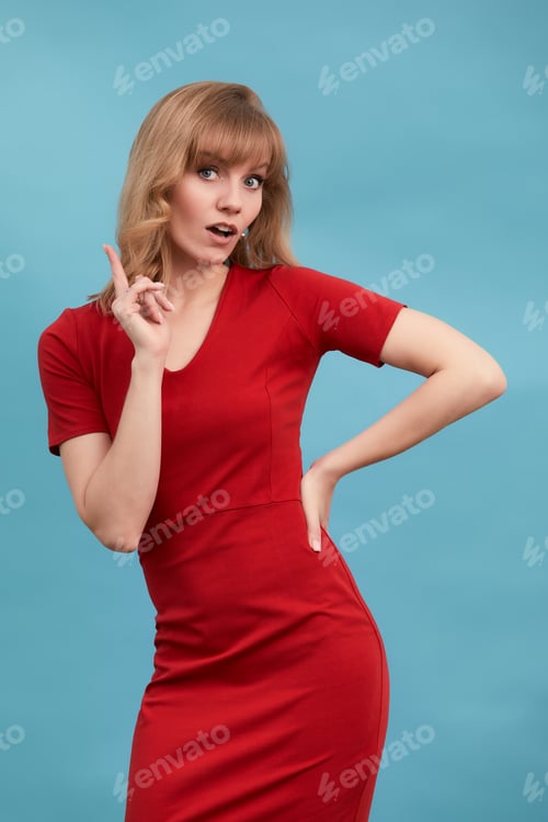 Preview: Happy surprised blonde young female smiling broadly at camera, pointing fingers away, showing