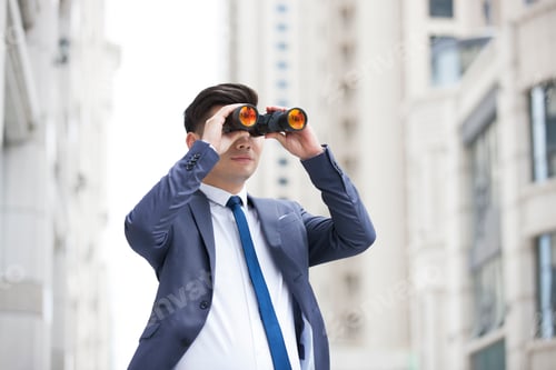 Preview: Confident businessman looking through binoculars