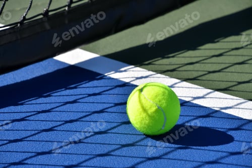 Preview: A yellow green tennis ball on a bright cobalt blue tennis court. lights shadows