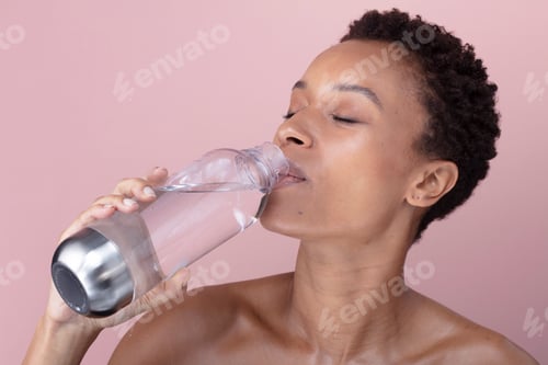 Preview: Studio shot of woman drinking water from bottle