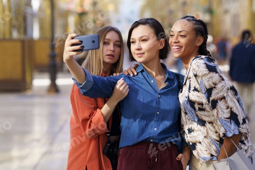 Preview: Trendy girlfriends taking selfie on street