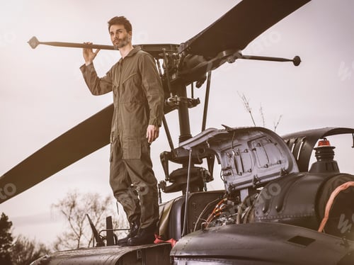 Preview: Man in overall standing on top of a helicopter