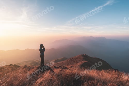 Preview: Young man traveler looking beautiful landscape at sunset on mountain