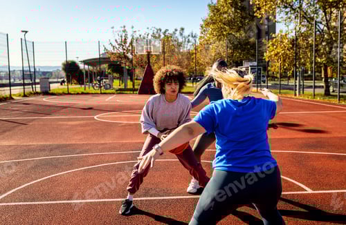 Preview: Diverse group of young woman having fun playing recreational basketball outdoors.