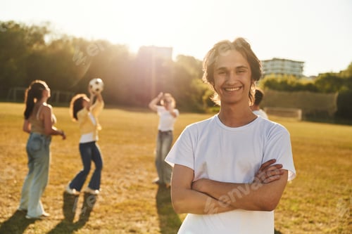 Preview: Arms crossed, standing. Young friends are having fun on the field with soccer ball