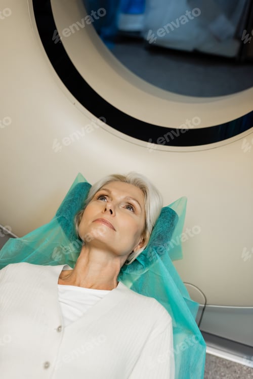 Preview: high angle view of blonde woman lying during diagnostics on ct scanner in hospital