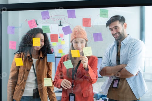 Preview: Multiethnic young business people brainstorming on a project by writing on the glass wall