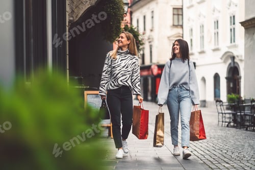 Preview: Two young women on a shopping spree in the city center, walking around with paper shopping bags in