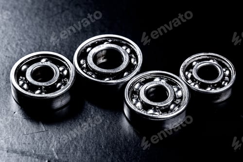 Preview: Close up view of four ball bearings on a black surface during the evening