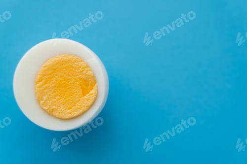 Preview: Close up view of cut boiled egg on blue background