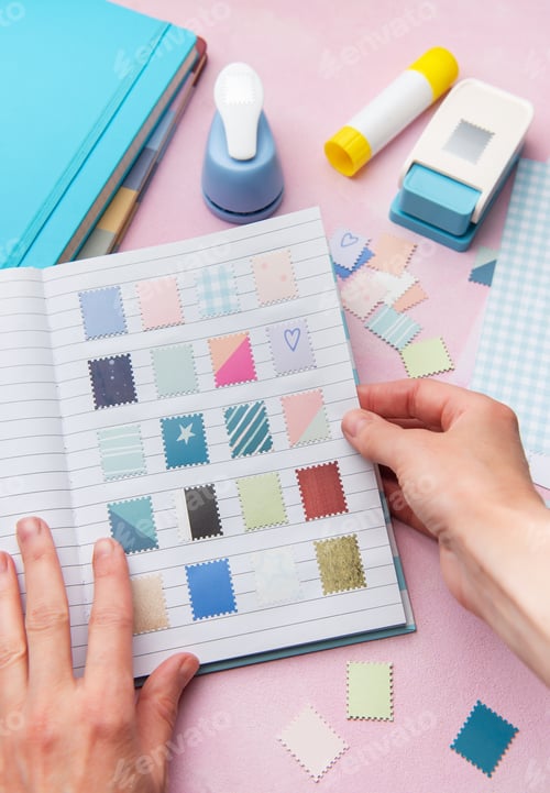 Preview: Hands creating a scrapbook with decorative paper punches