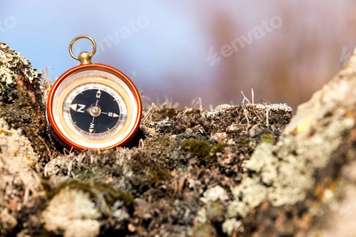 Preview: Compass on rock against blurred background, space for text. Camping equipment