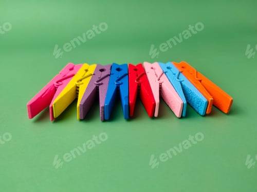 Preview: The image shows a row of colorful wooden clothespins on a green background.