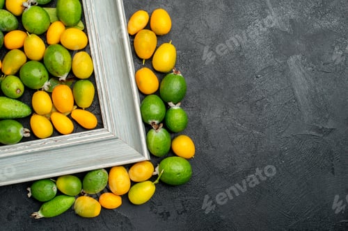 Preview: Above view of collection of citrus fruits in picture frame and around it on dark background