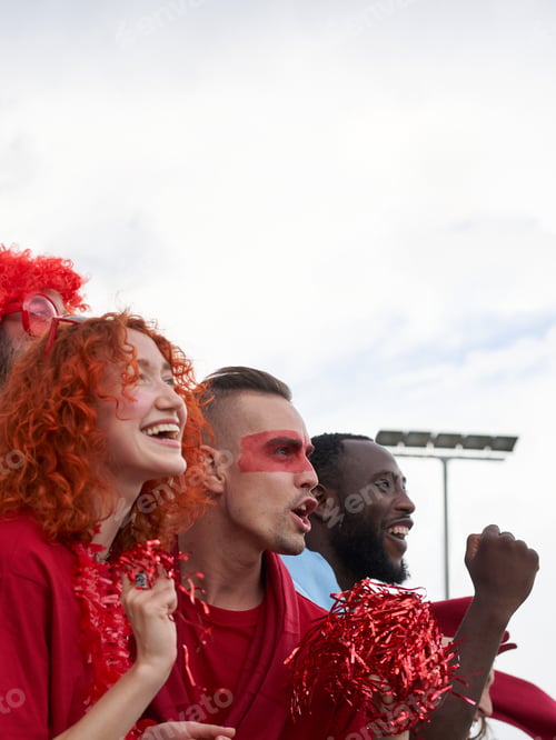 Preview: Vertical photo of a group of people of different races follow the soccer match in the parking lot.