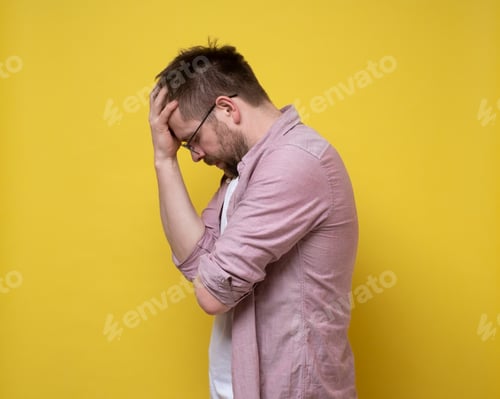 Preview: Bearded man with glasses is upset or has a headache, he closes eyes and holds forehead with hand