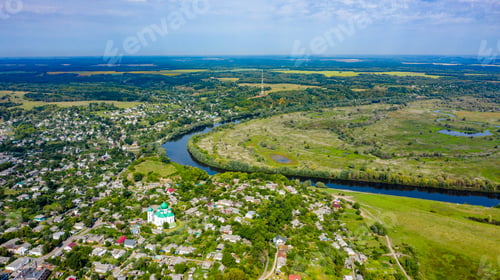Preview: Aerial view of a small city on a beautiful summer day with a green landscape behind it.