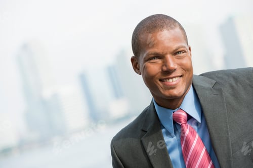 Preview: A young man in a business suit with a blue shirt and red tie. Smiling at the camera.