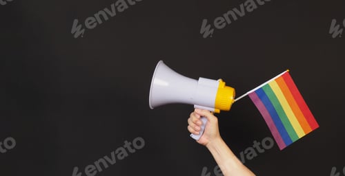 Preview: Hand is hold Rainbow pride flag and megaphone on black background.