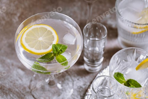Vista previa: Varios vasos en bandeja plateada llenos de bebidas frías con hielo, limón y menta