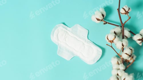 Preview: Sanitary napkin with wings and cotton flowers on mint or Tiffany Blue background.top angle view