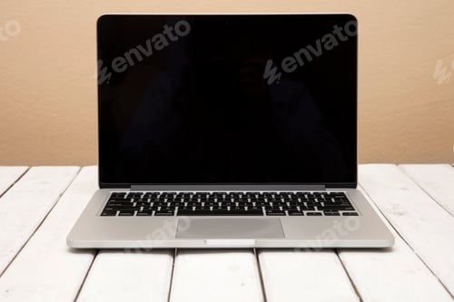 Preview: Laptop with black screen on white wooden table by orange background