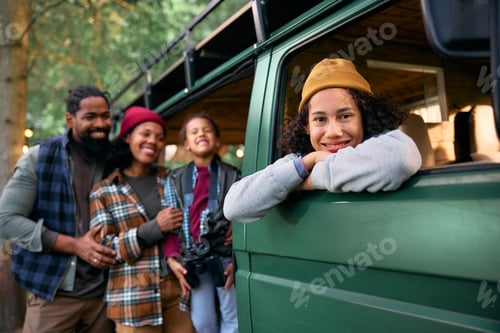 Preview: Happy black kid in camper trailer during family trip in nature looking at camera.
