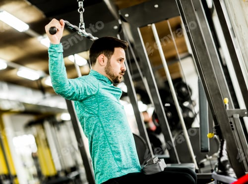 Preview: Young man doing exercise for triceps in the gym on mashine