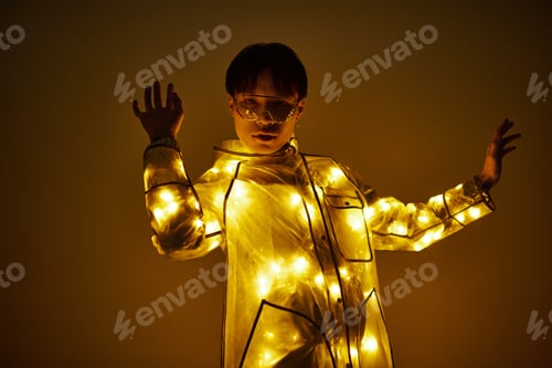 Preview: Stylish young man in illuminated outfit striking a striking pose under soft yellow lights