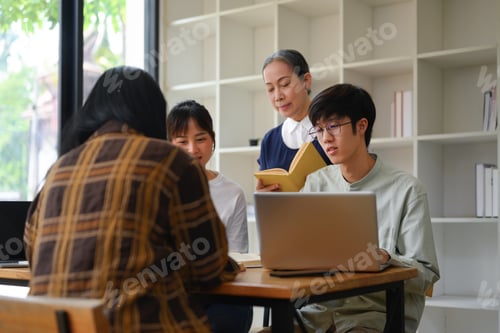 Preview: Happy mature professor helping group of students at university library