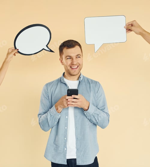 Preview: Holding smartphone. Many ideas. Man standing in the studio with empty signs for the text
